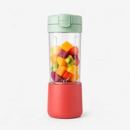 Coral portable blender filled with colorful fruit.
